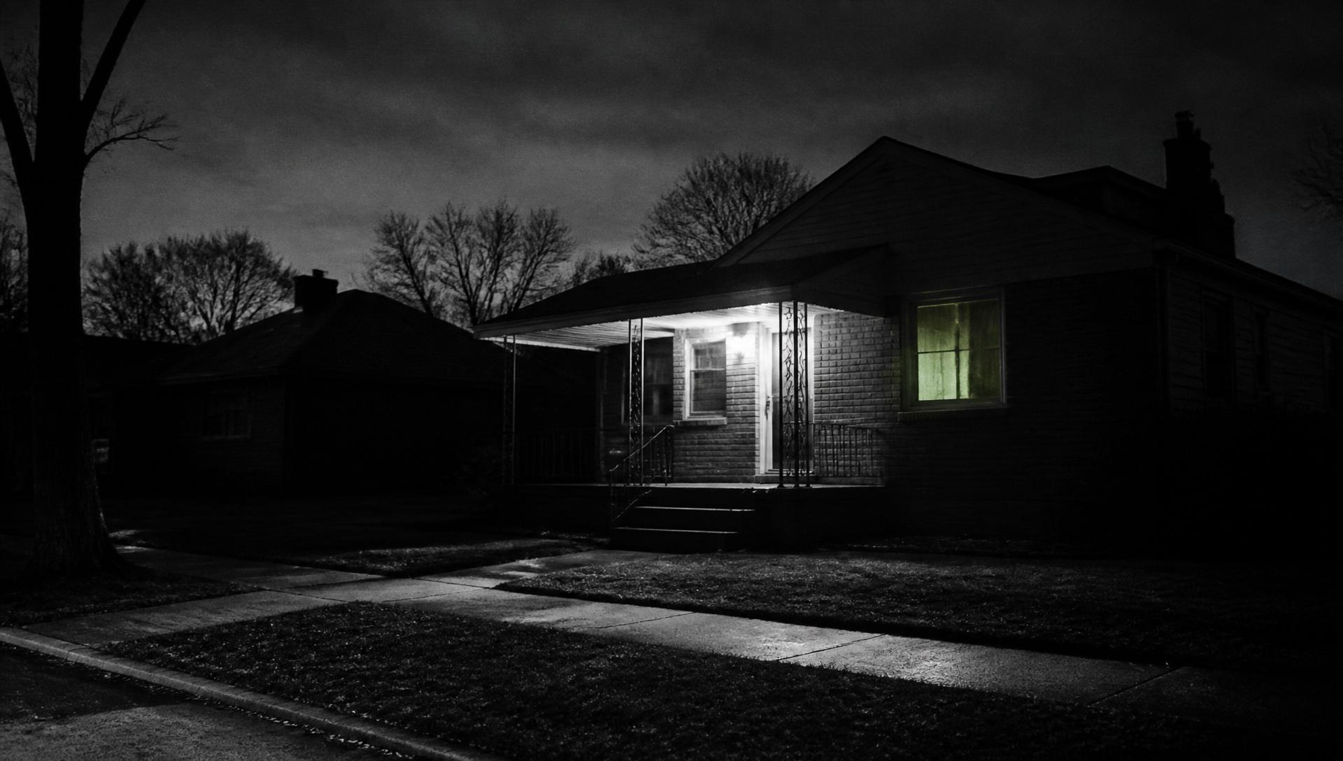 A single-story house on the east side, one window glowing faintly green.